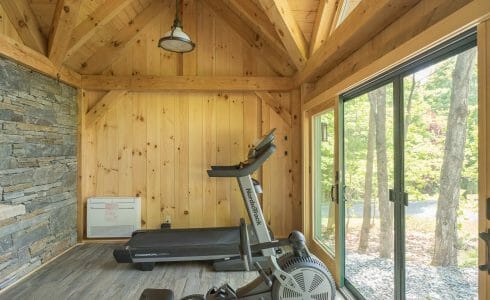 Exercise equipment in the Workout room and barn with stone wall and sliding glass doors, fabricated from rough sawn white pine