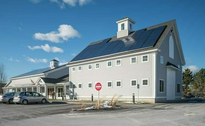 Exterior of The Hopkinton Art Center with solar panels and a white washed timber entry way