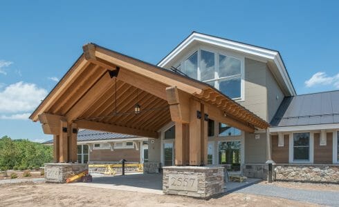 The Mahamudra Buddhist Retreat in Cragsmoor, NY has a heavy timber entryway and interior trusses fabricated from Glulam and Douglas Fir. The entryway features scrolls and black steel