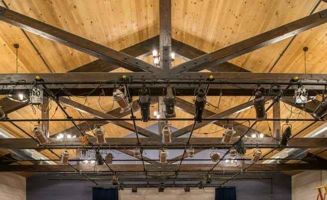 Timber Trusses with steel plates and mounted stage lights in a performance space in the Hopkinton Art Center