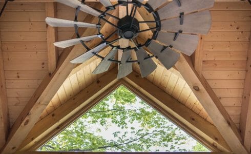 Overhead industrial farm fan with skylight in a timber frame post and beam workout room barn