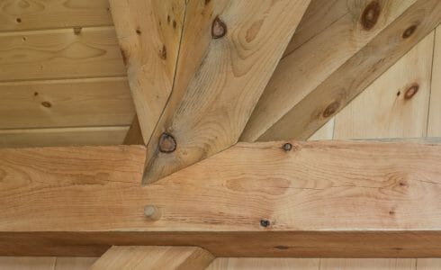 Complex joinery in a timber frame workout room made from rough sawn white pine