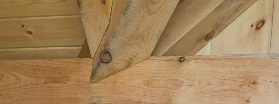 Complex joinery in a timber frame workout room made from rough sawn white pine