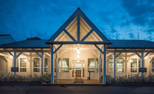 The VTel porch with post, beams, and king post trusses, has been fabricated with planed Douglas fir and painted white.