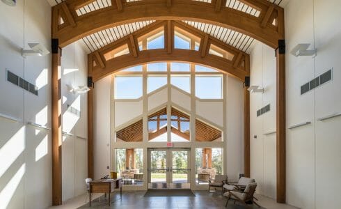 Interior of Mahamudra Buddhist retreat with high ceilings and glulam arches.