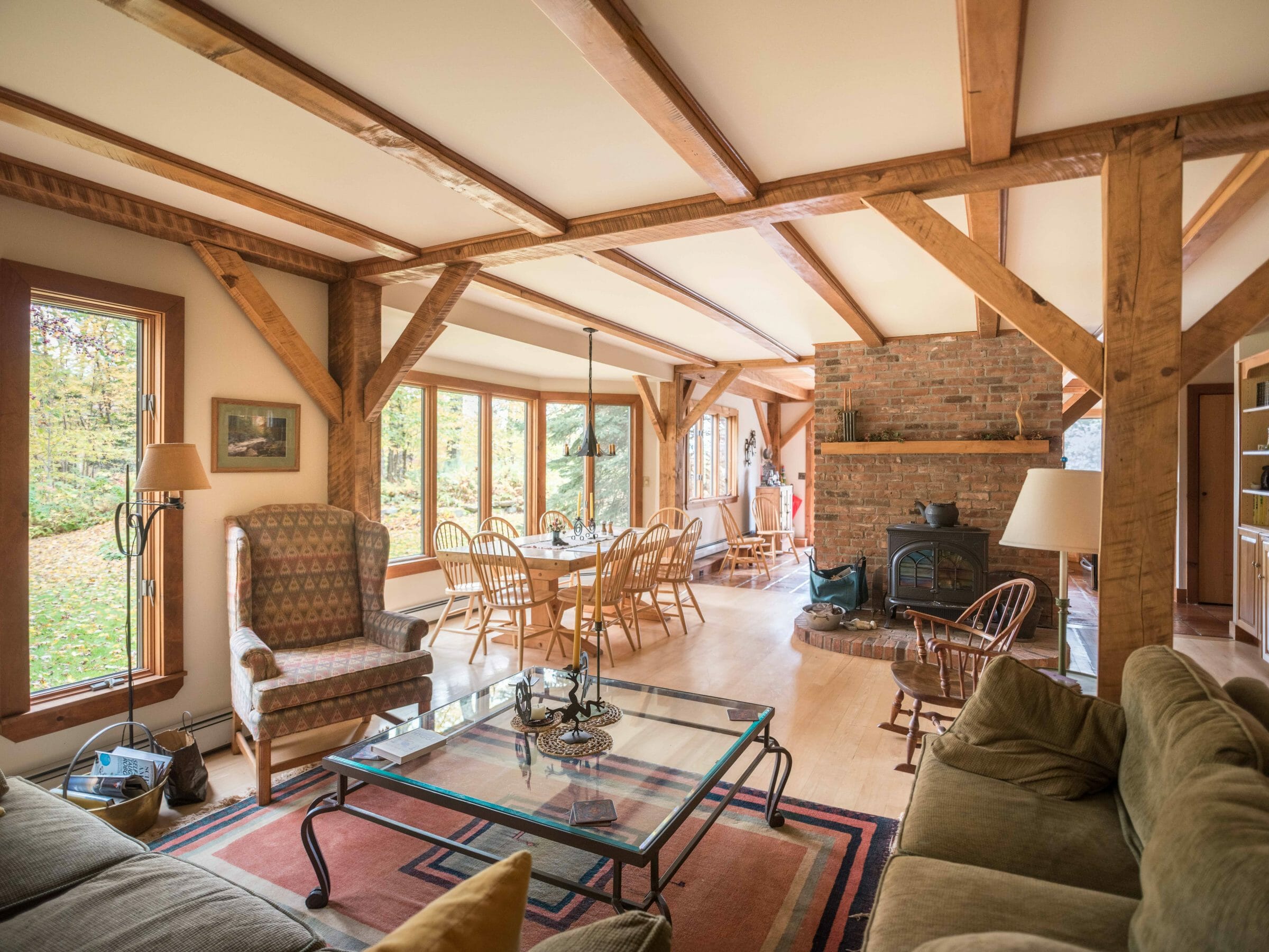 Vermont Retreat for sale with gathering room with wood posts and beams and stove and brick hearth