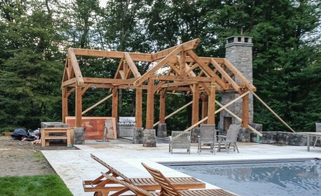 Pool House Timber Frame in CT. Pool patio with fireplace and rustic heavy timber pavilion.