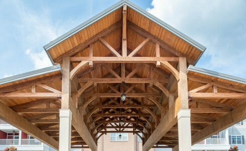 The Crossings at West Shore in Enola, PA. Timber Frame Porte Cochere Entry Way with Heavy Timber King Post Trusses and Stone Post Bases.