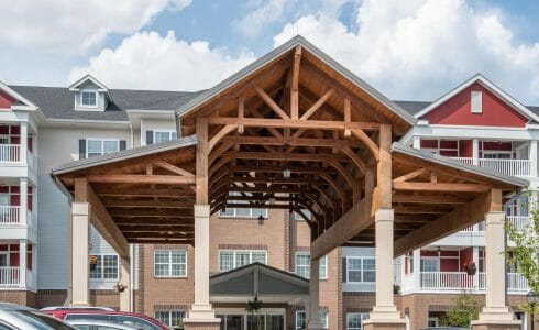 The Crossings at West Shore in Enola, PA. Timber Frame Porte Cochere Entry Way with Heavy Timber King Post Trusses and Stone Post Bases.