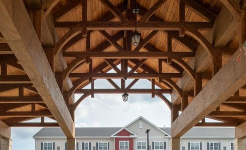 The Crossings at West Shore in Enola, PA. Timber Frame Porte Cochere Entry Way with Heavy Timber King Post Trusses and Stone Post Bases.