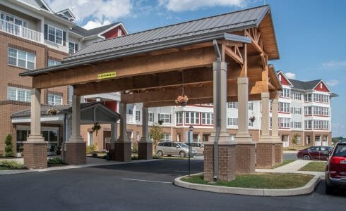 The Crossings at West Shore in Enola, PA. Timber Frame Porte Cochere Entry Way with Heavy Timber King Post Trusses and Stone Post Bases.