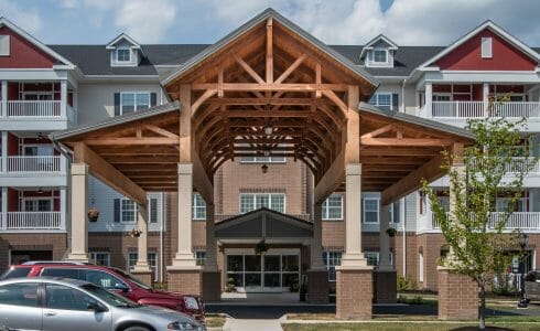 The Crossings at West Shore in Enola, PA. Timber Frame Porte Cochere Entry Way with Heavy Timber King Post Trusses and Stone Post Bases.