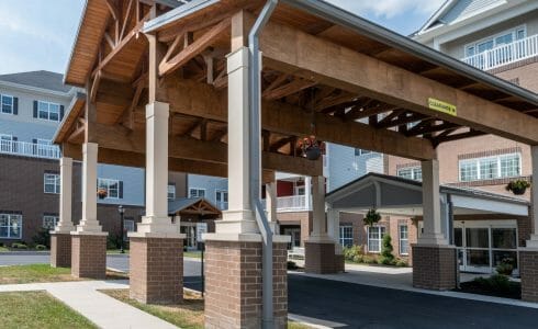 The Crossings at West Shore in Enola, PA. Timber Frame Porte Cochere Entry Way with Heavy Timber King Post Trusses and Stone Post Bases.