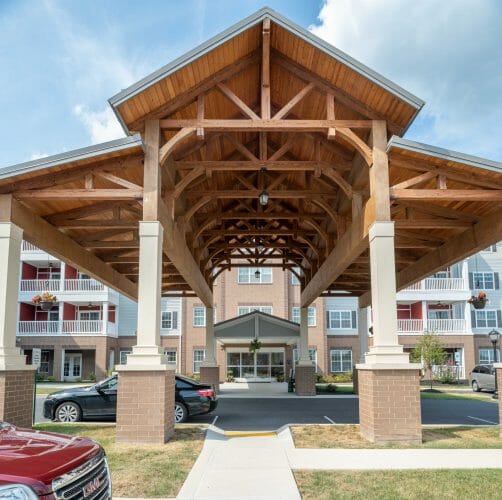 The Crossings at West Shore in Enola, PA. Timber Frame Porte Cochere Entry Way with Heavy Timber King Post Trusses and Stone Post Bases.