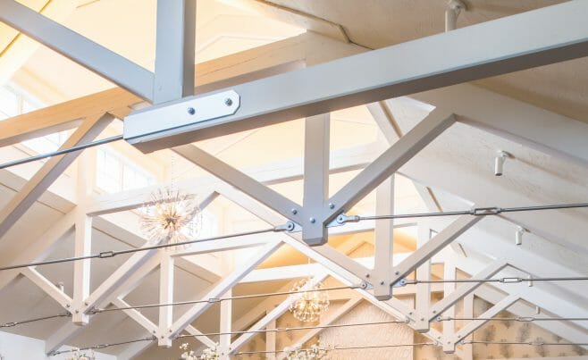 Steel tie bar and steel plate joinery details on a white timber truss in the Anya Restaurant in Thompson, CT.