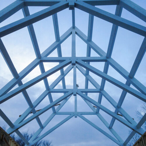 Scissor trusses with a dramatic pitch that have been stained white for a private chapel/pool building