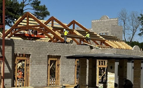 Installation of conventional roof framing on a heavy timber truss.