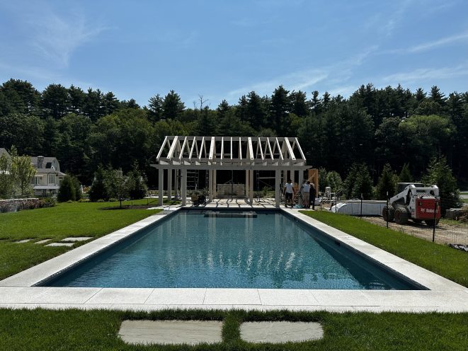 Timber frame pool house by a swimming pool.